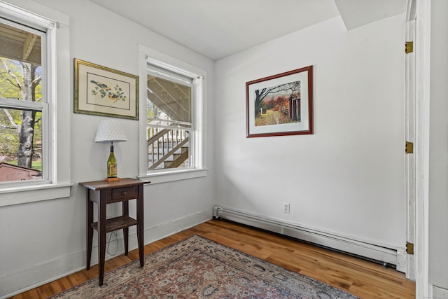 interior space featuring a baseboard heating unit and wood finished floors