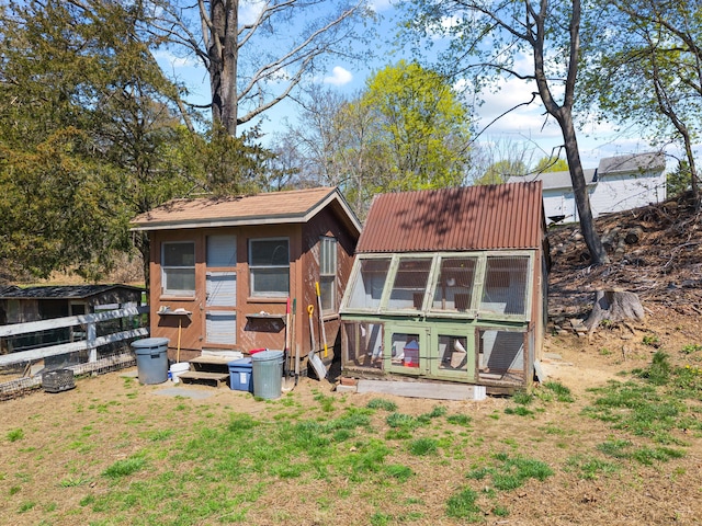 rear view of house featuring metal roof, exterior structure, and an outbuilding