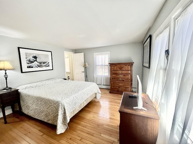 bedroom with a baseboard radiator and light wood-type flooring