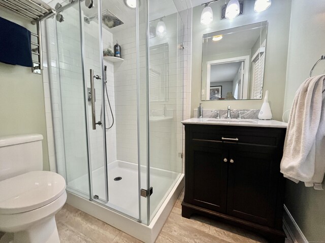 full bath with toilet, a stall shower, wood finished floors, and vanity