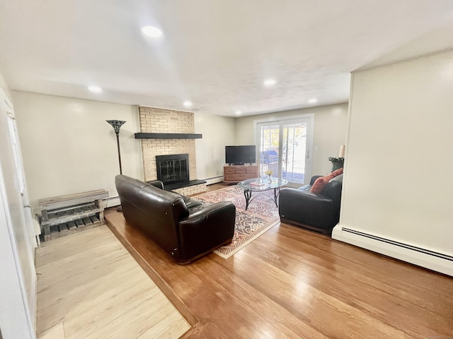 living area featuring baseboard heating, wood finished floors, and a fireplace
