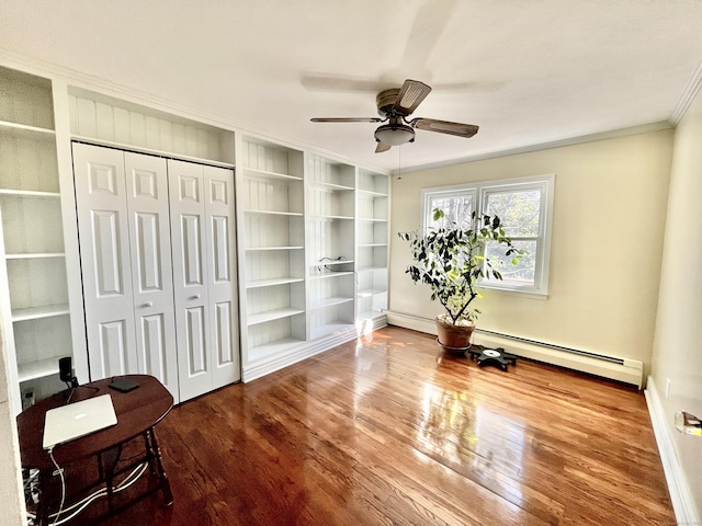 interior space with a closet, baseboards, a baseboard radiator, crown molding, and wood finished floors