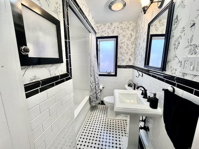 full bathroom with visible vents, toilet, tile walls, wallpapered walls, and a wainscoted wall