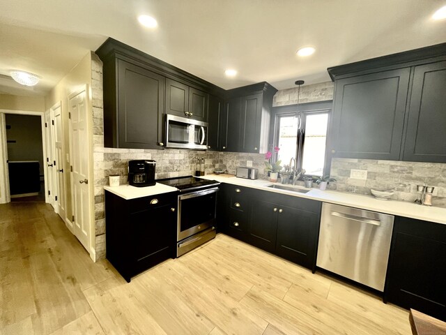 kitchen with backsplash, light countertops, appliances with stainless steel finishes, and light wood-type flooring