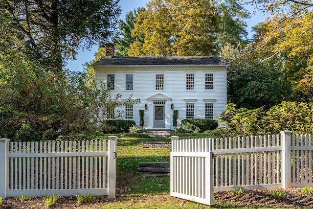colonial house with fence private yard and a chimney
