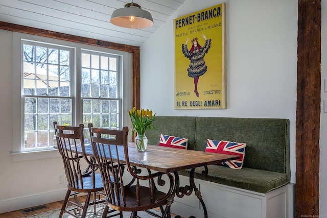 dining area featuring baseboards, visible vents, wood finished floors, and lofted ceiling