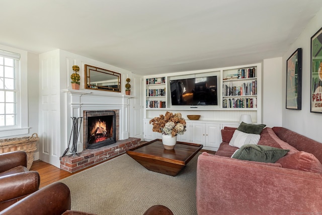 living room featuring built in features, a fireplace, and wood finished floors