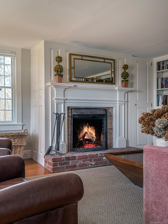 sitting room featuring a brick fireplace and wood finished floors
