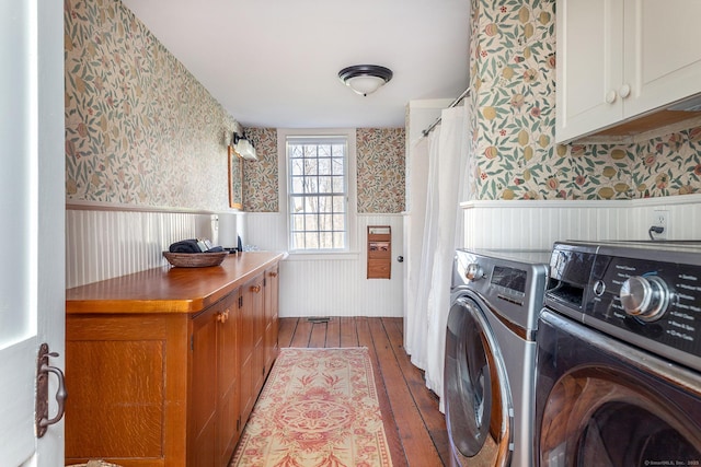 laundry area with dark wood-style flooring, wallpapered walls, washing machine and dryer, and a wainscoted wall