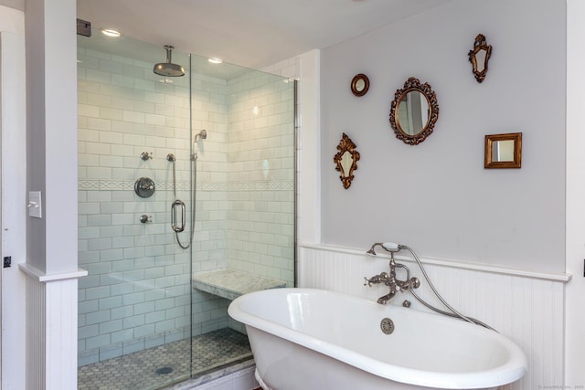full bath with wainscoting, a soaking tub, and a stall shower