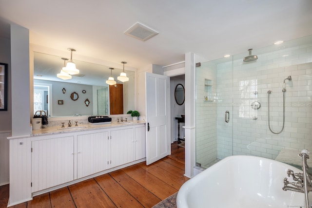 full bathroom with visible vents, hardwood / wood-style flooring, a soaking tub, a sink, and a stall shower