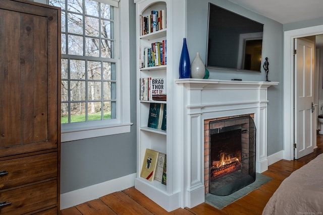 interior space featuring a fireplace with flush hearth, baseboards, and wood finished floors