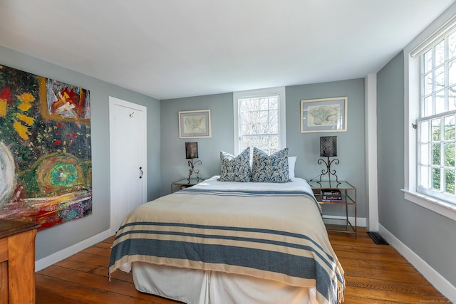 bedroom featuring baseboards, wood-type flooring, and visible vents