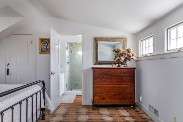 bedroom with visible vents, dark wood finished floors, ensuite bath, and vaulted ceiling