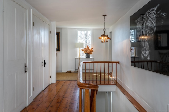 hallway featuring baseboards, an upstairs landing, and hardwood / wood-style floors