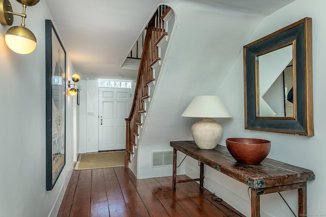 hall with wood-type flooring, baseboards, stairs, and visible vents