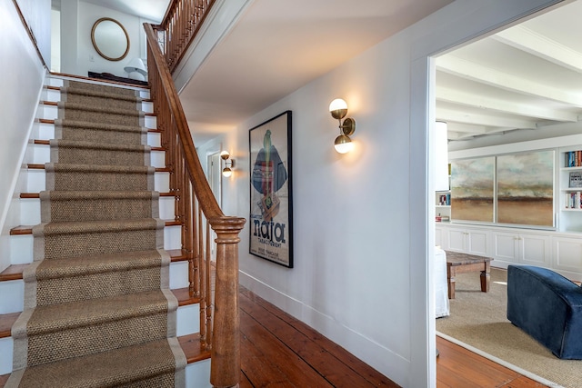 stairway featuring wood-type flooring, beamed ceiling, and baseboards