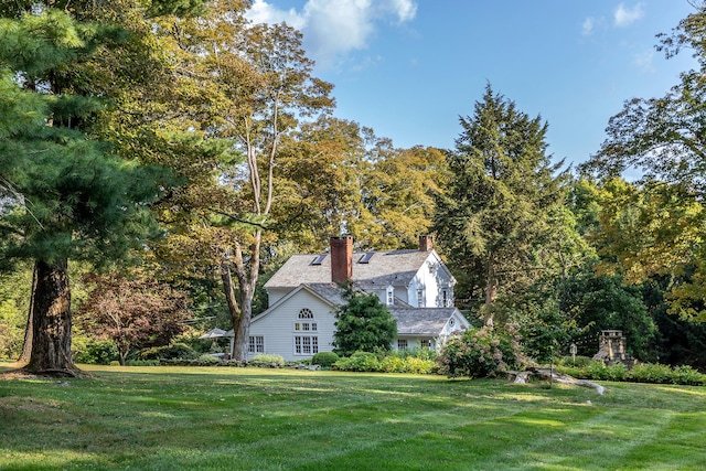 view of property exterior with a lawn and a chimney