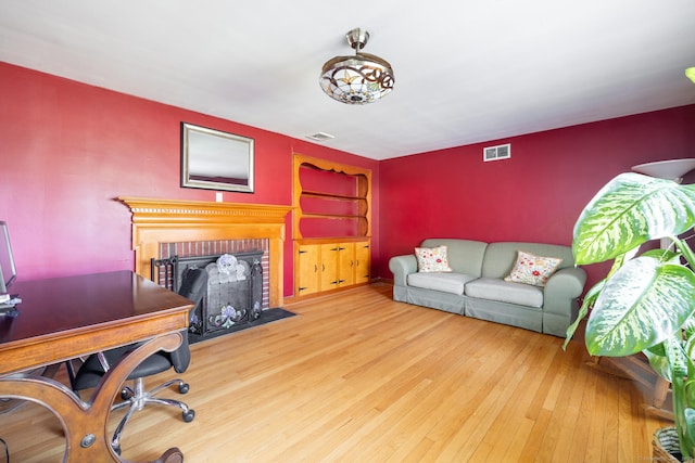 269 Silver Hill Rd, Derby, CT 06418 - home office with a brick fireplace, visible vents, an accent wall, and wood finished floors