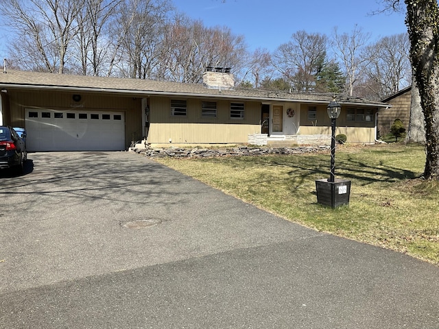 ranch-style home with a garage, a front yard, a chimney, and aphalt driveway