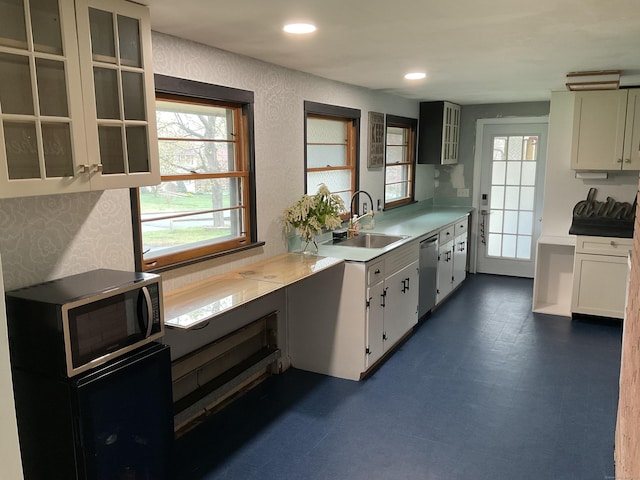 kitchen with stainless steel dishwasher, dark floors, a sink, glass insert cabinets, and light countertops