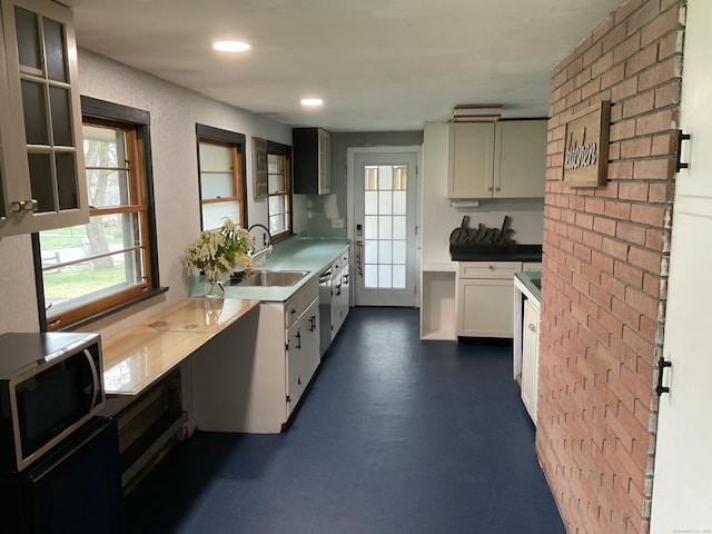 kitchen with recessed lighting, stainless steel dishwasher, a sink, glass insert cabinets, and white cabinetry