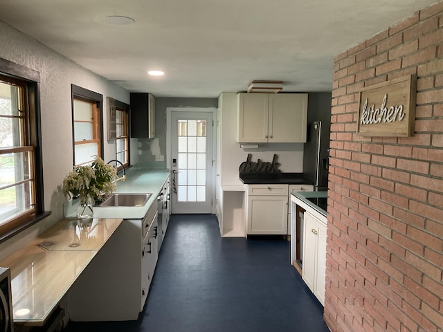 kitchen with white cabinets, dark floors, a sink, and a healthy amount of sunlight