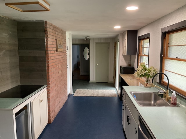 kitchen featuring stainless steel dishwasher, a sink, light countertops, white cabinetry, and recessed lighting