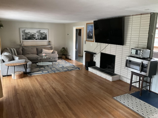 living room with wood finished floors, a fireplace, and a baseboard radiator