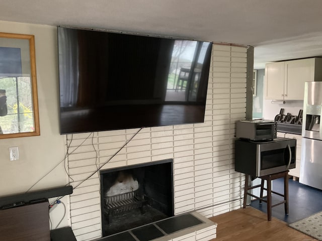 interior space with a fireplace with raised hearth, a toaster, and dark wood-style flooring