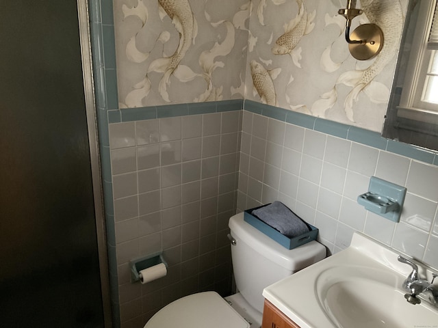 bathroom featuring toilet, vanity, and tile walls