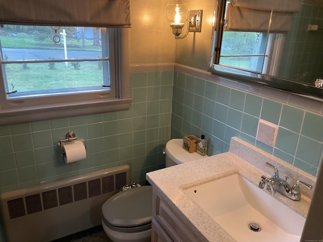bathroom featuring radiator heating unit, tile walls, vanity, and toilet