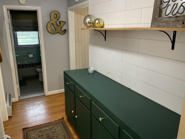 interior space with radiator heating unit, toilet, baseboards, and wood finished floors