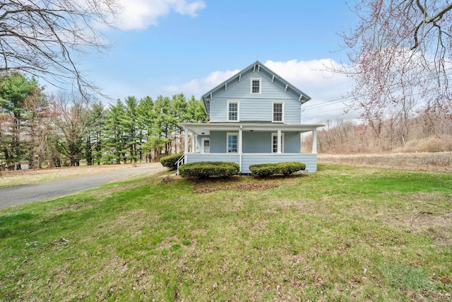 view of front of property with a porch, a front yard, and aphalt driveway