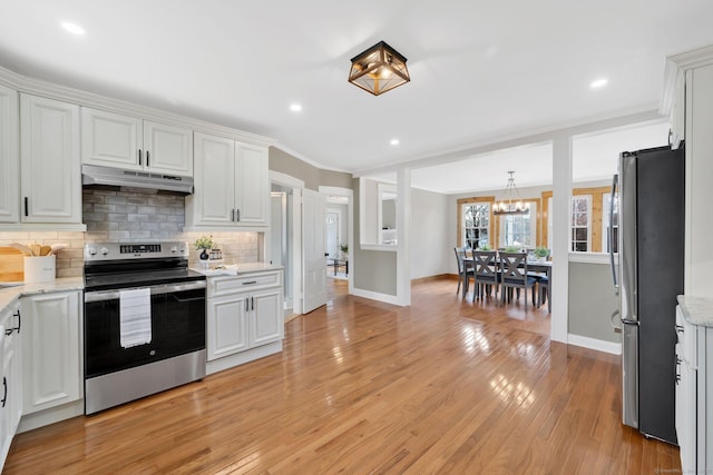 kitchen with decorative backsplash, appliances with stainless steel finishes, baseboards, an inviting chandelier, and under cabinet range hood