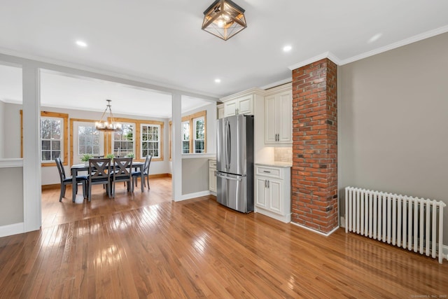 kitchen featuring baseboards, radiator, an inviting chandelier, and freestanding refrigerator