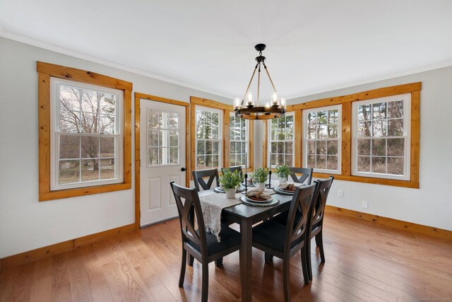 dining area with ornamental molding, an inviting chandelier, a wealth of natural light, and baseboards