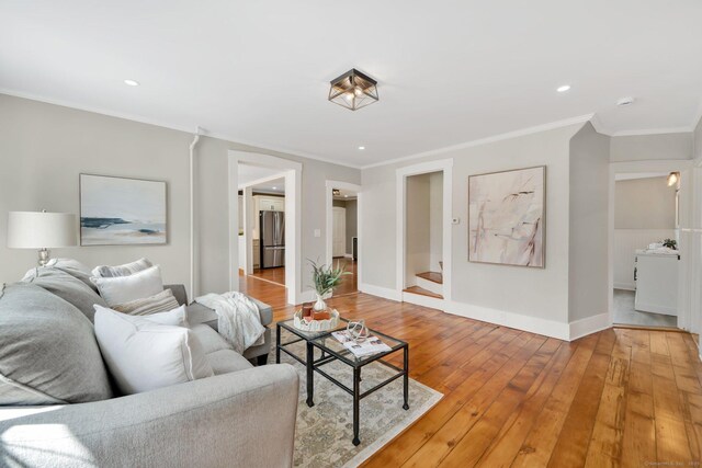 living room with light wood finished floors, recessed lighting, ornamental molding, and baseboards