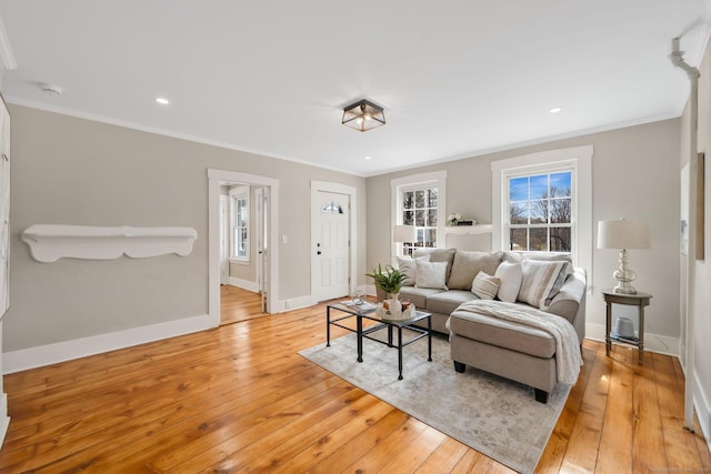 living room with light wood-type flooring, recessed lighting, ornamental molding, and baseboards