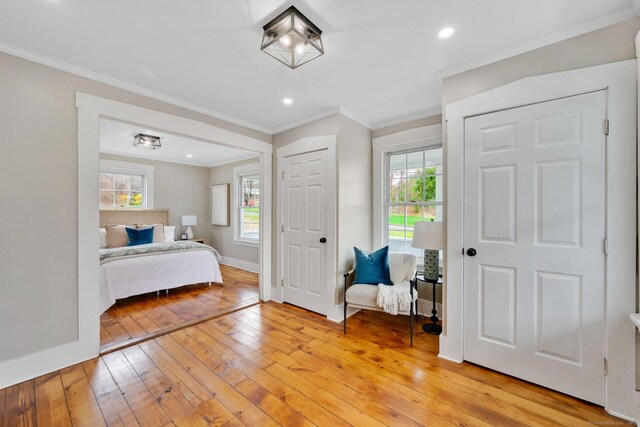 bedroom with ornamental molding, light wood finished floors, and baseboards