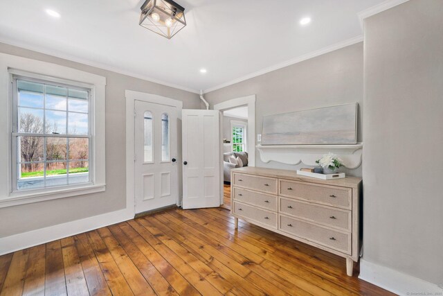 foyer with baseboards, hardwood / wood-style flooring, and ornamental molding