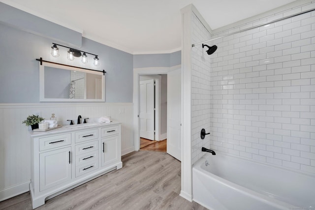 bathroom with crown molding, tub / shower combination, wood finished floors, vanity, and wainscoting