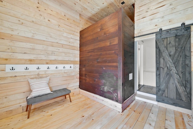 unfurnished room with hardwood / wood-style floors, wood walls, and a barn door