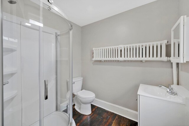 bathroom with toilet, wood finished floors, a shower stall, and baseboards