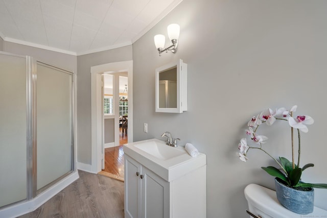 full bathroom featuring a shower stall, crown molding, toilet, wood finished floors, and vanity