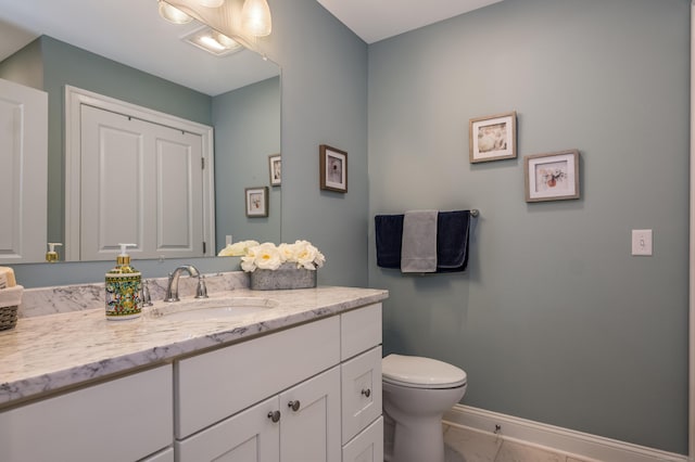 bathroom with toilet, baseboards, and vanity