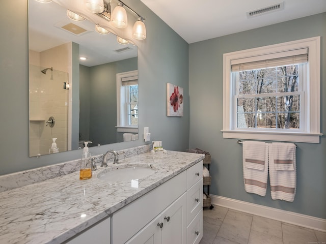 full bath featuring visible vents, baseboards, a tile shower, and vanity