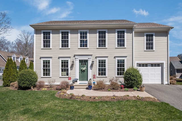 colonial-style house featuring driveway, a front lawn, entry steps, and a garage