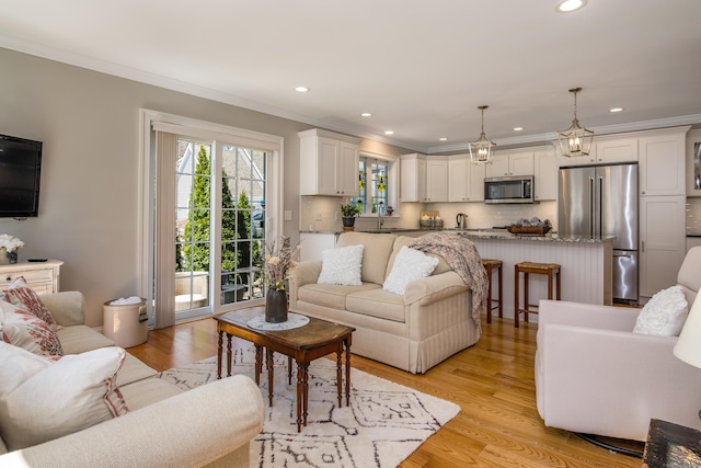 living room with ornamental molding, light wood finished floors, and recessed lighting