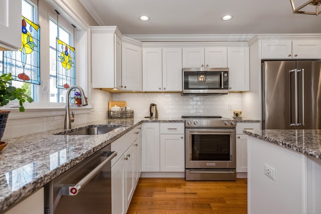 kitchen featuring a sink, light stone countertops, stainless steel appliances, and white cabinetry